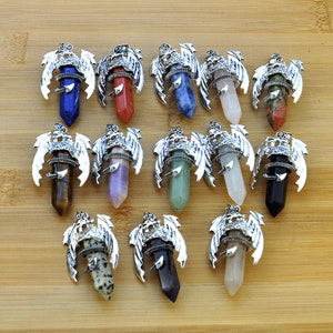 May include: Twelve silver dragon pendant charms with different colored gemstone points. The pendants feature a detailed dragon design with wings and a crown.