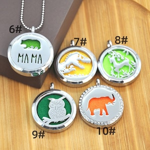 May include: Six silver locket pendants with different animal designs. The lockets are on a wooden surface. The lockets are numbered 6 through 10. The lockets have a green, yellow, or orange background. The lockets have a silver chain attached to them. The lockets have a small opening on the side to add essential oils.