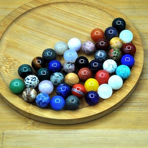 May include: A collection of 30 colorful gemstone beads, each approximately 1 cm in diameter. The beads are arranged in a circular pattern on a wooden surface. The beads are a variety of colors, including red, blue, green, yellow, and brown.