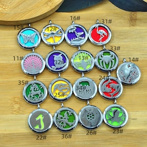 May include: A collection of round, silver-toned pendants with various designs, including a butterfly, dragonfly, owl, and octopus. Each pendant has a colored background and is numbered. The pendants are displayed on a wooden surface.