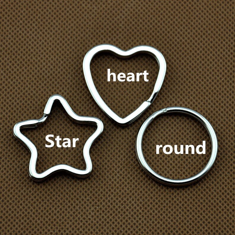 Puede incluir: Tres llaveros plateados de diferentes formas: un coraz&oacute;n, una estrella y un c&iacute;rculo. El llavero en forma de coraz&oacute;n tiene la palabra "coraz&oacute;n" inscrita en &eacute;l, el llavero en forma de estrella tiene la palabra "estrella" inscrita en &eacute;l y el llavero en forma de c&iacute;rculo tiene la palabra "redondo" inscrita en &eacute;l.