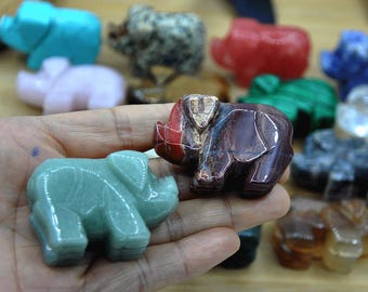 May include: A collection of small, hand-carved elephant figurines made from various types of stone. The elephants are in different colors, including green, red, brown, and white.