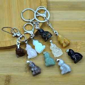 May include: A set of ten keychains featuring different colored stone carvings of cats. The keychains are attached to silver key rings.