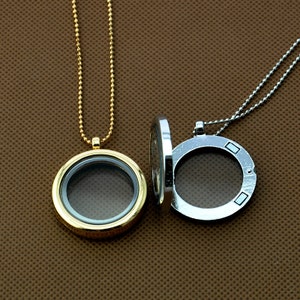 May include: Two silver locket necklaces with clear glass inserts. One necklace has a gold chain and the other has a silver chain.