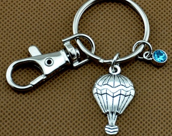 Keychain with the word serene stamped on a washer with hot air balloon charm and green crystal.
