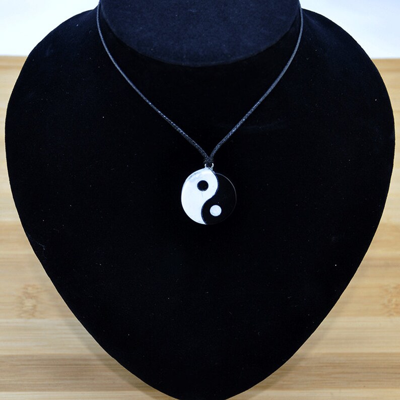 May include: A black necklace with a round black and white yin yang pendant.