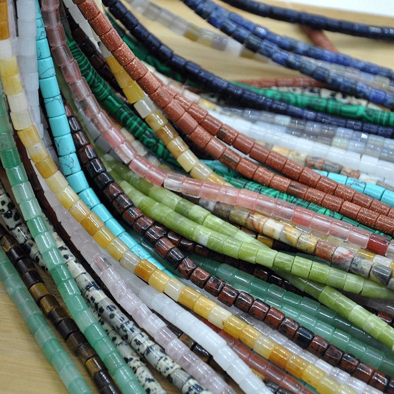 May include: Assortment of colorful gemstone beads, each strand featuring a different type of stone. The beads are square-shaped and have a polished finish. The colors include green, blue, red, brown, white, and yellow.