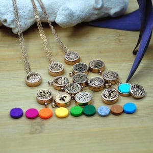 May include: Rose gold-coloured essential oil diffuser necklaces with various engraved designs. Includes a selection of colourful felt pads. The necklaces have delicate chains and round pendants. The felt pads come in purple, pink, orange, yellow, green, and blue.