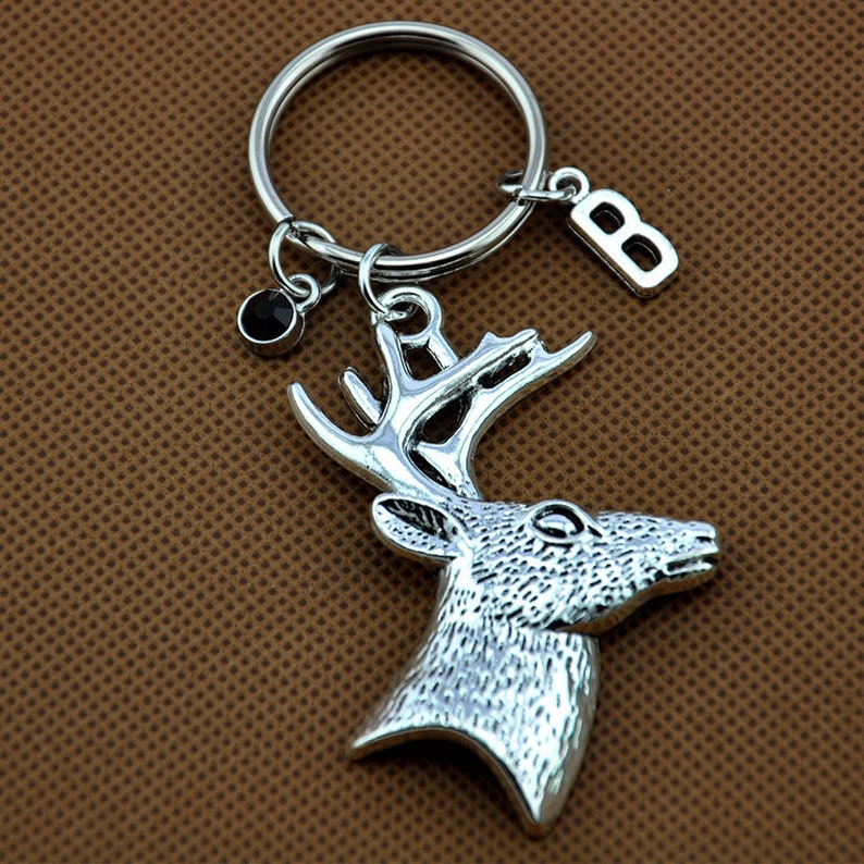 May include: Silver-toned deer head keychain with a black crystal charm and a silver letter 'B' charm attached to a silver key ring.