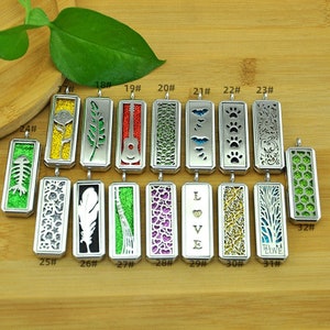 Puede incluir: Una colección de colgantes rectangulares plateados con varios diseños. Los colgantes presentan patrones recortados, incluyendo una rosa, una guitarra, huellas de patas y la palabra "LOVE". Algunos colgantes tienen fondos de purpurina de colores.