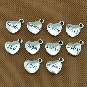 Puede incluir: Doce encantos de coraz&oacute;n plateados con diferentes palabras de miembros de la familia, incluyendo "abuelo", "abuela", "t&iacute;o", "t&iacute;a", "pap&aacute;", "mam&aacute;", "hermana", "hermano", "hijo" e "hija".