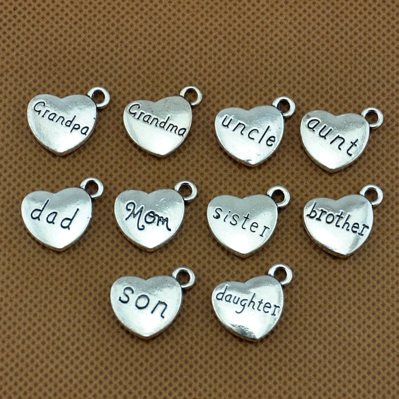 Puede incluir: Doce encantos de coraz&oacute;n plateados con diferentes palabras de miembros de la familia, incluyendo "abuelo", "abuela", "t&iacute;o", "t&iacute;a", "pap&aacute;", "mam&aacute;", "hermana", "hermano", "hijo" e "hija".