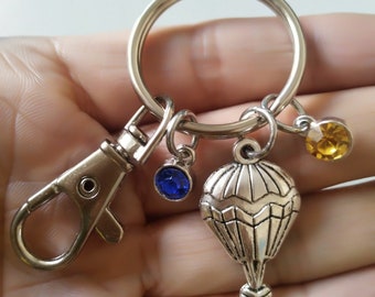 Keychain with the word serene stamped on a washer with hot air balloon charm and green crystal.