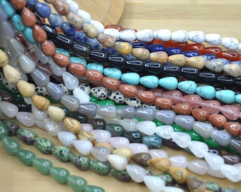 May include: A close-up shot of various strands of teardrop-shaped gemstone beads. The beads are in a variety of colors, including turquoise, brown, black, white, and green. The beads are strung together, ready for jewelry making.