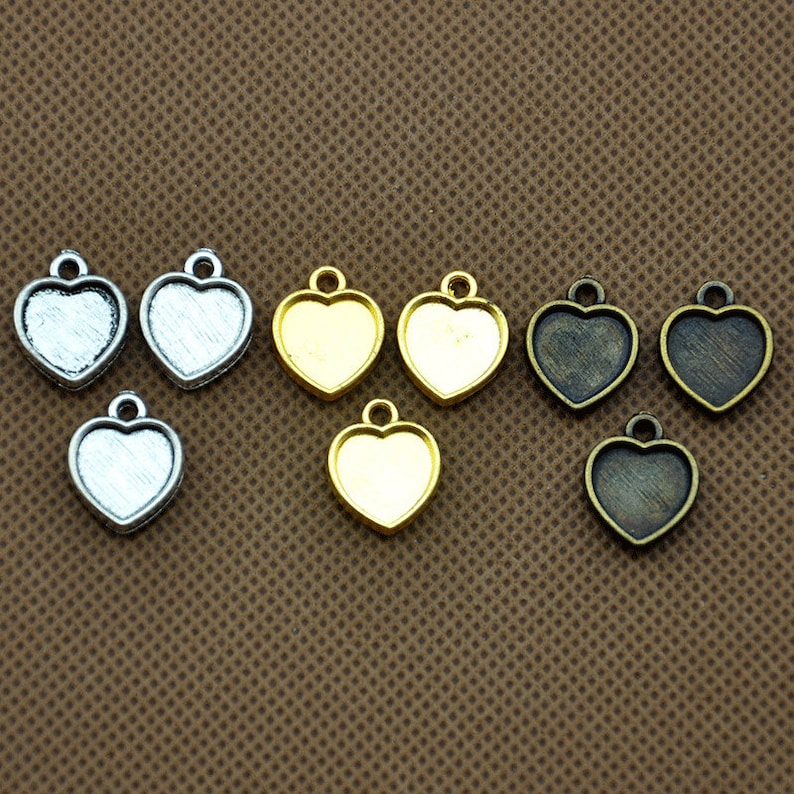 May include: Eight heart-shaped metal charms with a clear glass centre. The charms are in three colours: silver, gold, and bronze.