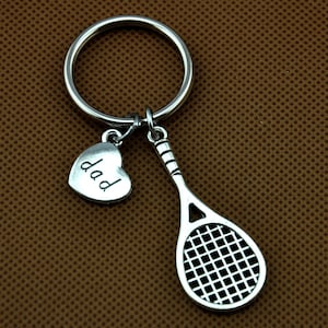 Puede incluir: Llavero de raqueta de tenis de plata con un dije de coraz&oacute;n que dice "pap&aacute;".
