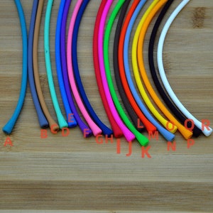 May include: A collection of eighteen flexible, smooth, cylindrical silicone cords arranged in a fan pattern, each labeled with a red letter from A to R, featuring a diverse spectrum of colors including blue, tan, teal, pink, red, green, and white.