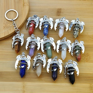 May include: Twelve silver dragon pendant charms with different colored gemstone points. Each charm features a detailed dragon design with wings and a coiled tail.