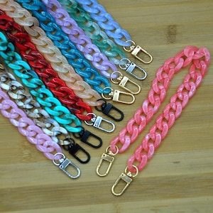 May include: Assortment of colorful plastic chain straps with silver and gold lobster clasps. The chains are various shades of pink, blue, green, and red.