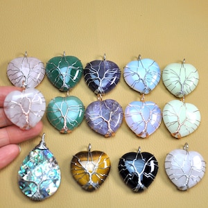 Peut inclure: Assortiment de pendentifs en forme de cœur avec des motifs d'arbres en fil de fer. Les pendentifs sont faits de différentes pierres, notamment du quartz rose, de l'améthyste, de l'aventurine verte et du quartz clair.