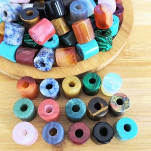 May include: A collection of colourful gemstone beads in various shapes and sizes. The beads are arranged in a bowl and on a wooden surface.