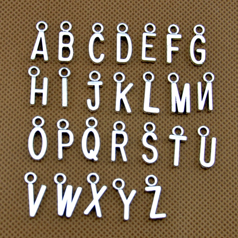 May include: Silver alphabet letter charms with a loop for attaching to jewelry or crafts. The letters are arranged in alphabetical order from A to Z.