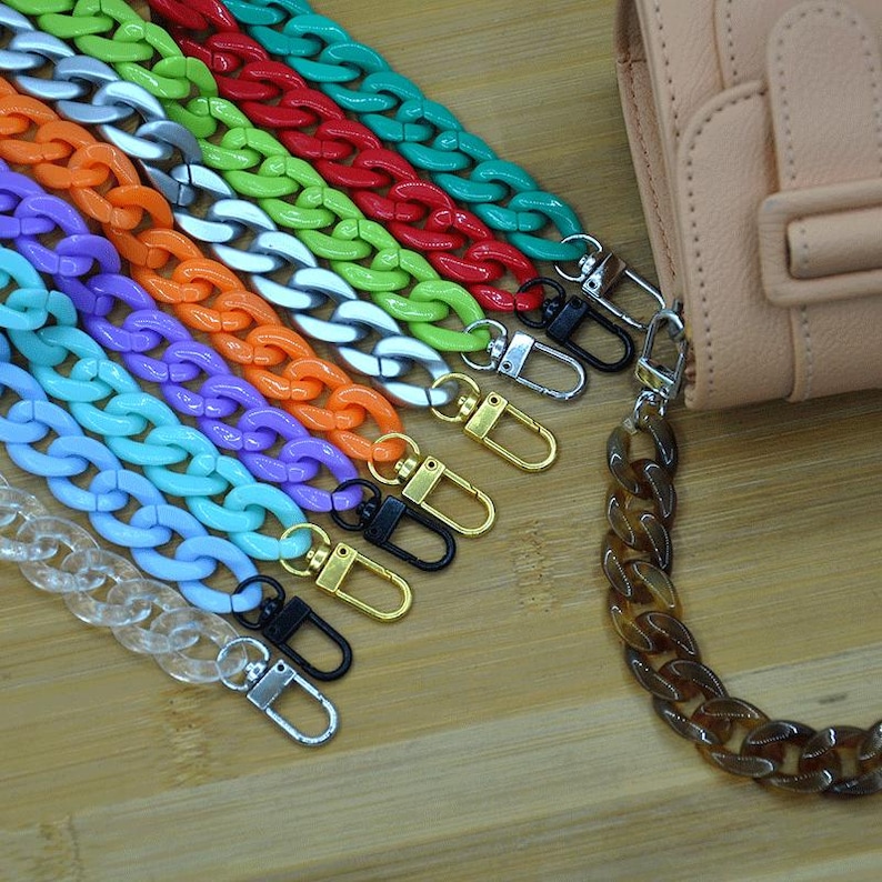 May include: Assortment of colorful plastic chain bag straps with metal clasps. The chains are in various colors, including clear, light blue, purple, orange, green, silver, red, and turquoise.