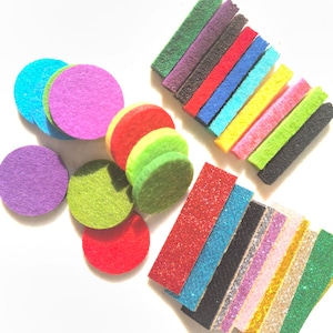 Puede incluir: Surtido de círculos y formas rectangulares de fieltro de colores. Los círculos son de varios colores, incluyendo morado, verde, rojo y azul. Los rectángulos son de un arcoíris de colores, incluyendo verde, morado, rojo, azul, amarillo, rosa y negro.