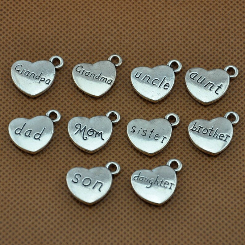 Puede incluir: Doce dijes de plata en forma de coraz&oacute;n con diferentes palabras de miembros de la familia grabadas en ellos. Las palabras son: "Grandpa", "Grandma", "Uncle", "Aunt", "Dad", "Mom", "Sister", "Brother", "Son", "Daughter".