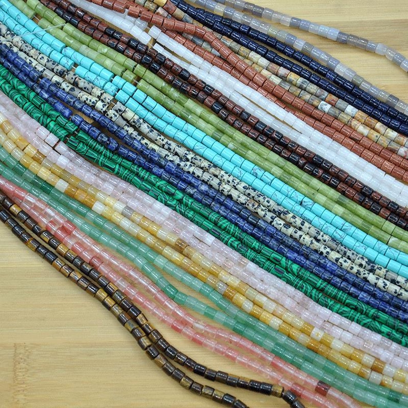 May include: Assortment of colorful gemstone beads, including turquoise, malachite, jasper, and agate. The beads are arranged in rows and are all approximately the same size.