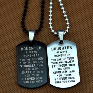 May include: Two dog tag necklaces. One is black with a black beaded chain, the other is silver with a silver beaded chain. Both tags have the same engraved message: "DAUGHTER ALWAYS REMEMBER..." and other inspirational words.