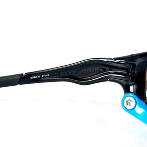 May include: Black Oakley sunglasses with a blue temple arm and the text "RADAR JACKET" on the frame.