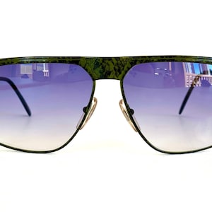 May include: Green aviator sunglasses with a textured frame and gradient purple lenses.
