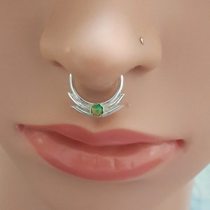 Op de afbeelding: Een zilveren neusring met een groene opaal edelsteen en een halve maan ontwerp.