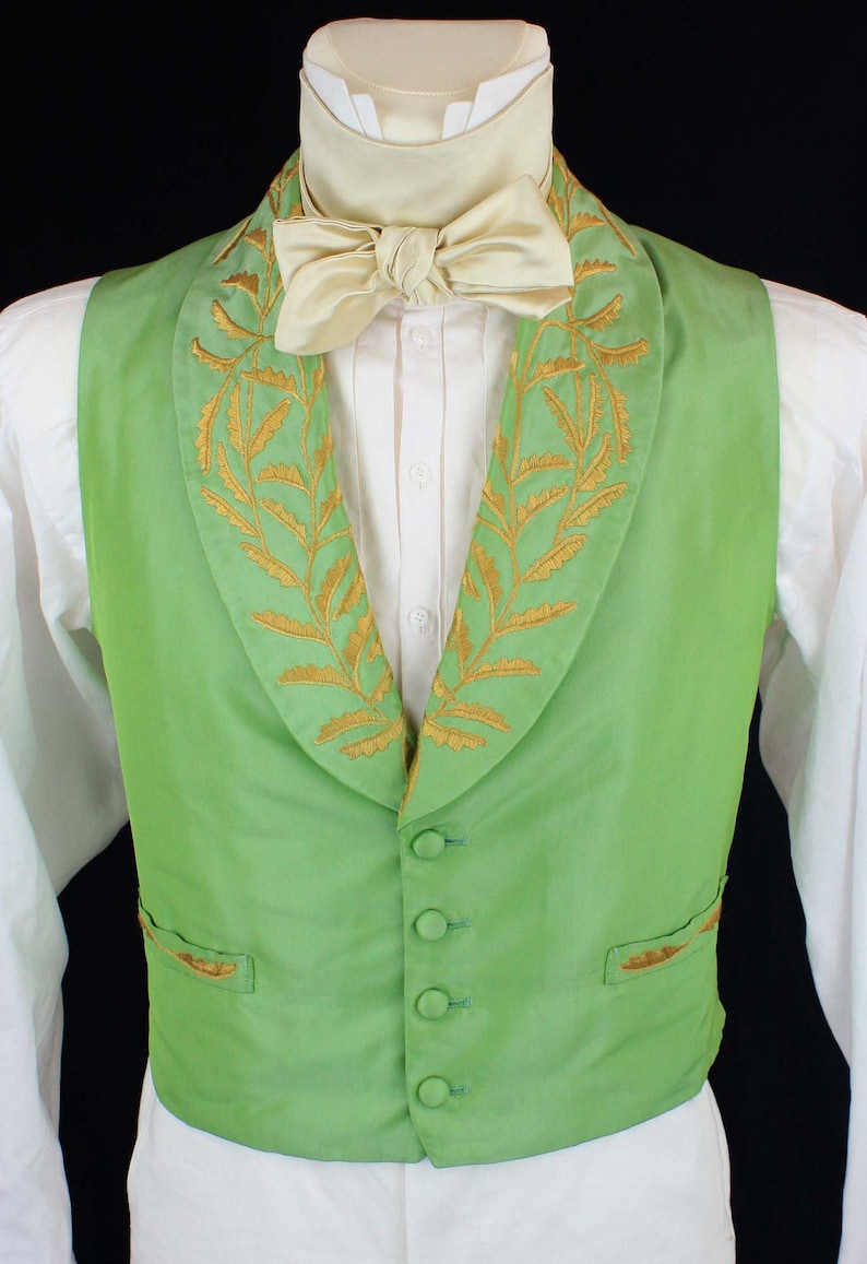 May include: A green vest with a gold embroidered floral pattern around the collar. The vest has five buttons and a pocket on the left side.