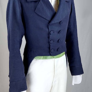 May include: A navy blue tailcoat with a white shirt and a cream-colored bow tie. The tailcoat has a double-breasted closure with four buttons and a long, pointed tail.
