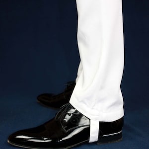 May include: White pants with a white cuff detail worn with black patent leather shoes.