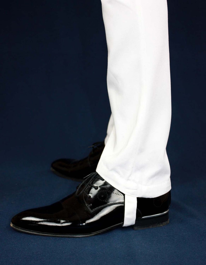 May include: White pants with a white cuff detail worn with black patent leather shoes.