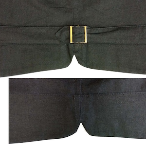 May include: The back of a black vest with a gold buckle. The vest has a seam down the center back and two pockets on the bottom.