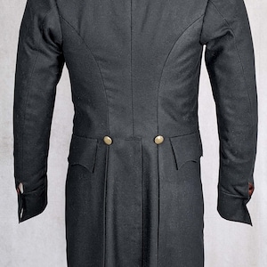 May include: A black tailcoat with a high collar and two gold buttons on the back. The coat has a long, flowing tail and is made of a fine, smooth fabric.