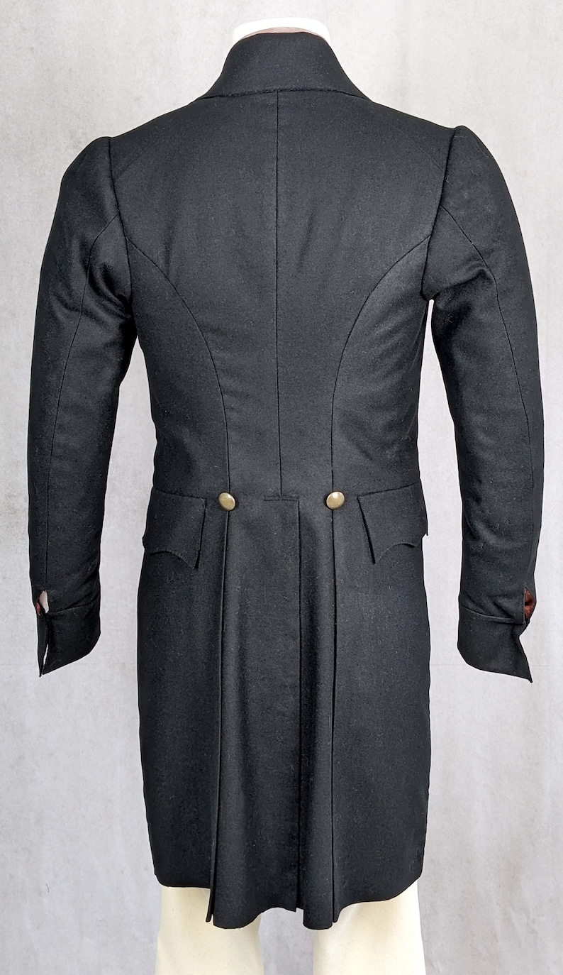 May include: A black tailcoat with a high collar and two gold buttons on the back. The coat has a long, flowing tail and is made of a fine, smooth fabric.