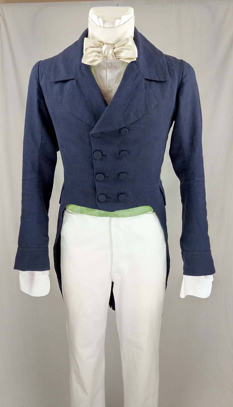 May include: A navy blue tailcoat with a double-breasted closure and five buttons. The tailcoat has a white shirt underneath with a cream-colored bow tie.