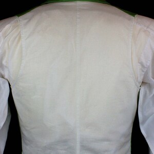 May include: A white vest with a green collar and gold trim. The vest is worn over a white shirt with a bow tie.