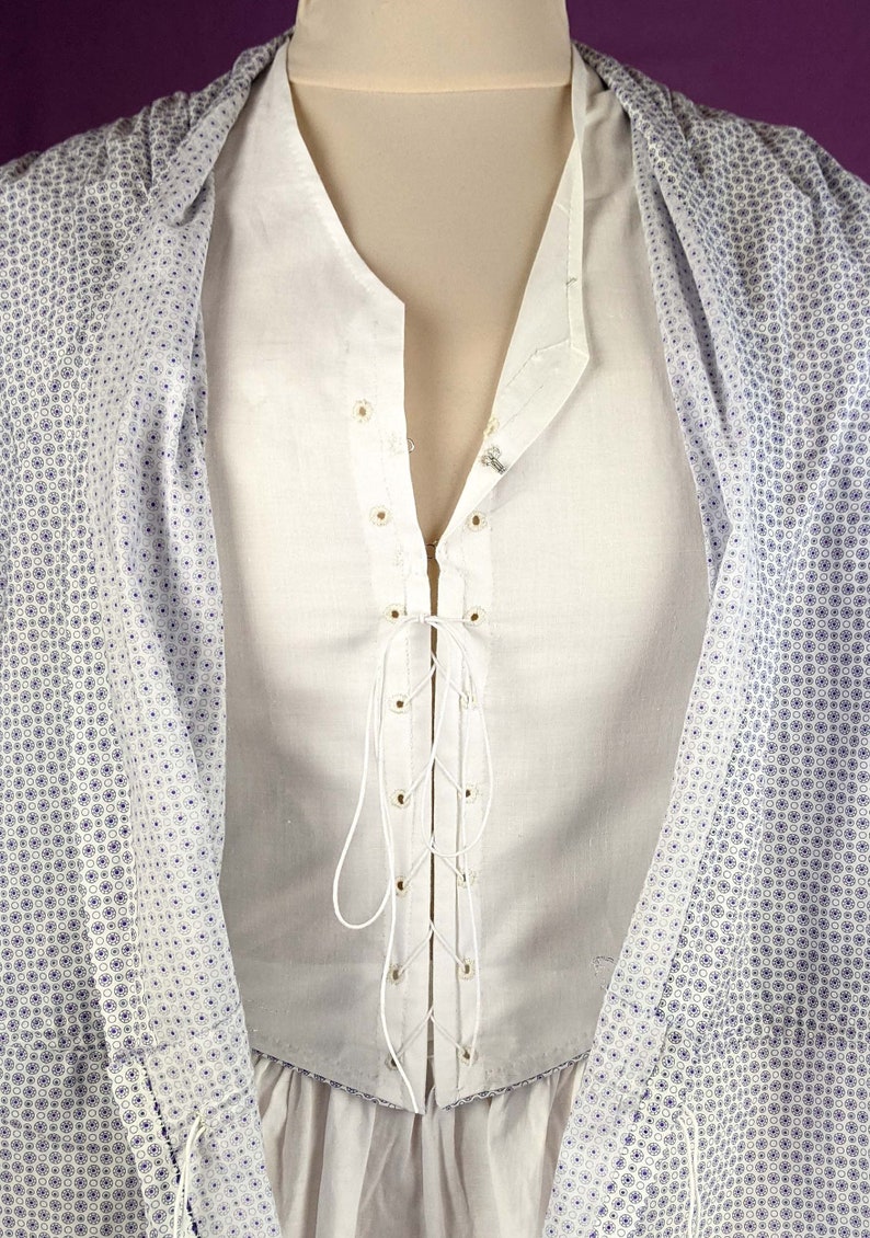 May include: A white shirt with a lace-up front and a white collar. The shirt is made of a lightweight fabric and has a relaxed fit.