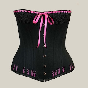 May include: A black corset with pink ribbon lacing and pink embroidery. The corset has a lace trim at the top and a satin finish.