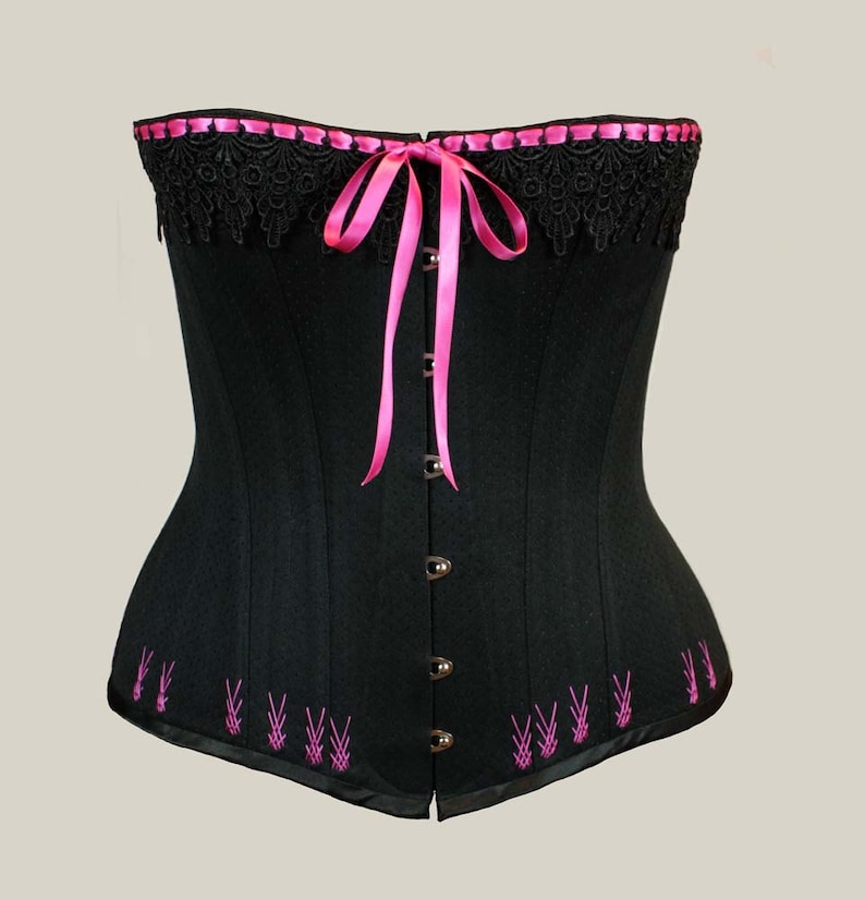 May include: A black corset with pink ribbon lacing and pink embroidery. The corset has a lace trim at the top and a satin finish.