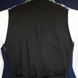 May include: Black waistcoat with a black adjustable strap and gold buckle. The waistcoat has a blue and white plaid lining.