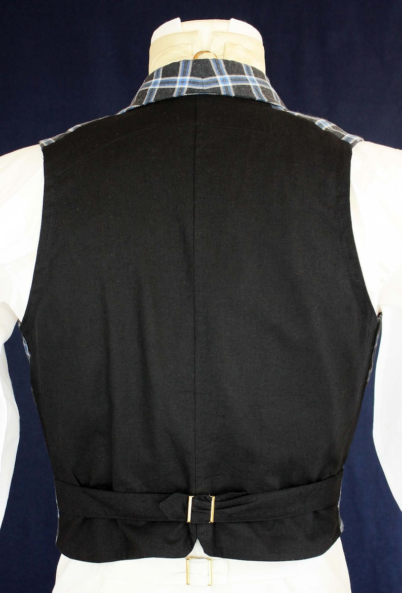 May include: Black waistcoat with a black adjustable strap and gold buckle. The waistcoat has a blue and white plaid lining.