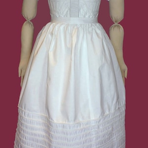 May include: A white cotton dress with a ruffled neckline and puffed sleeves. The dress has a fitted bodice and a full skirt with multiple layers of ruffles at the hem.