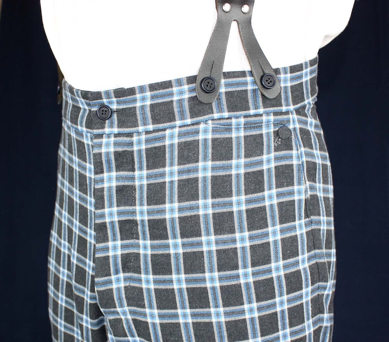 May include: Black and blue plaid pants with a button closure and suspenders. The suspenders are made of black leather and have a button closure.
